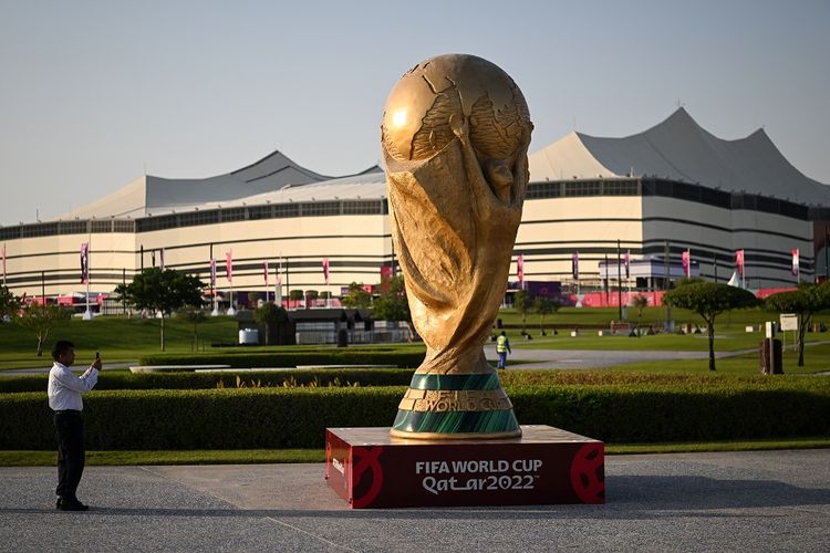 Seorang pria mengambil gambar replika trofi Piala Dunia FIFA di depan Stadion Al-Bayt di al-Khor pada 10 November 2022, menjelang turnamen sepak bola Piala Dunia 2022 Qatar. Piala Dunia 2022 dibuka dengan laga Qatar vs Ekuador pada Minggu (20/11/2022) malam WIB.