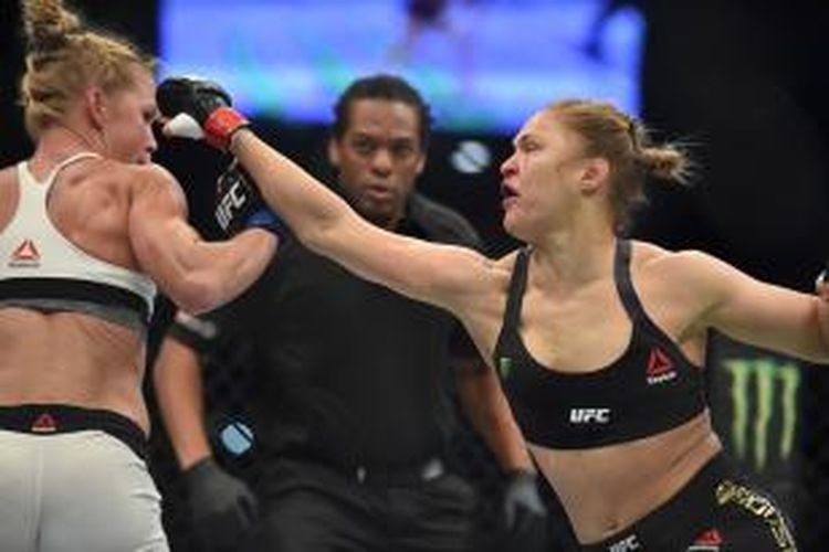 Petarung UFC asal Amerika Serikat, Ronda Rousy (kanan), melancarkan pukulan kepada sesama petarung AS, Holly Holm, pada pertarungan kelas bantam di Mebourne, Australia, Minggu (15/11/2015).