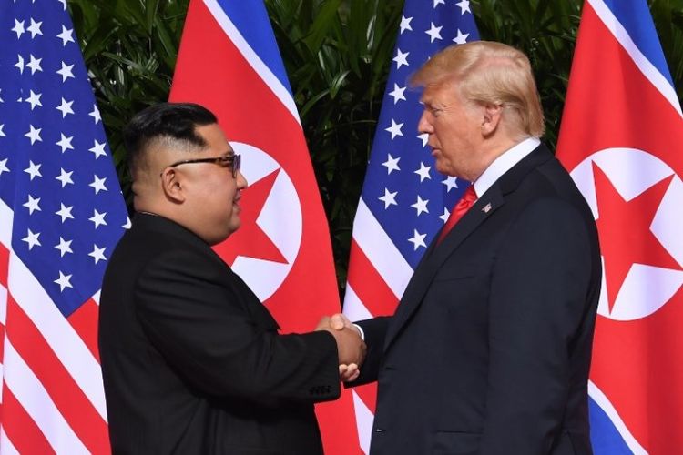 Pemimpin Korea Utara Kim Jong Un dan Presiden Amerika Serikat Donald Trump saling berjabat tangan untuk pertama kalinya di Hotel Capella, Singapura, Selasa (12/6/2018). (AFP/Saul Loeb)