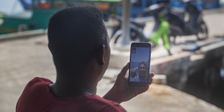 Heriman (42), seorang pengepul ikan tangkapan nelayan mengakses internet menggunakan gawai  di Teluk Baruk, Sepempang, Natuna, Selasa, 8 Oktober 2019.  