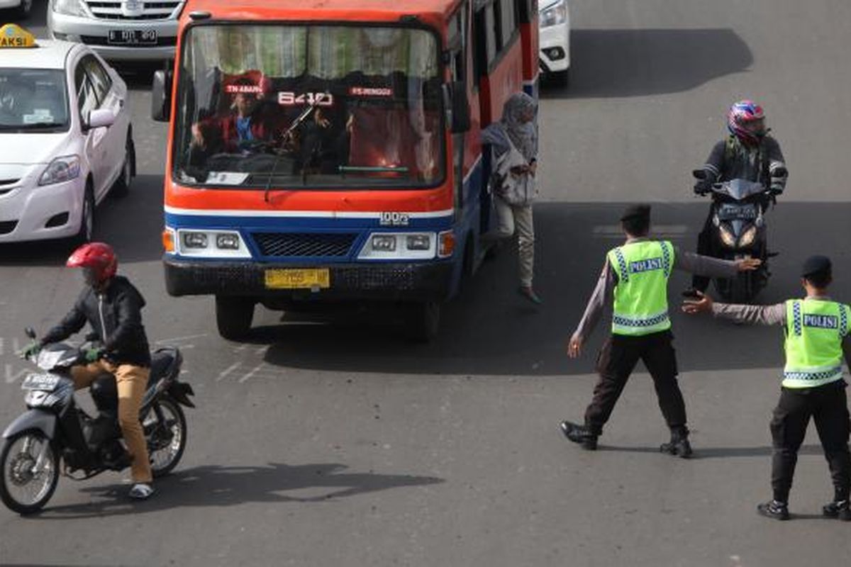 Gabungan petugas kepolisian dan Dinas Perhubungan DKI mengarahkan pengendara sepeda motor yang akan melintas di Jalan MH Thamrin, Jakarta Pusat, Rabu (17/12/2014). Di hari pertama uji coba pembatasan sepeda motor sepanjang Jalan Thamrin-Medan Merdeka Barat, masih terdapat sejumlah pengendara yang belum mengetahui aturan tersebut. KOMPAS/LUCKY PRANSISKA 