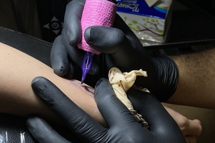 Tattoo Artist di Surabaya, Anggara Yuniarto saat merajah kulit pelanggannya menjadi karya seni tato, Selasa (25/2/2025).