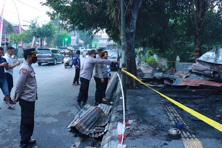 Polisi memasang garis di sekitar lokasi konter pulsa yang terbakar dan menewaskan dua orang di Jalan Letkol Isdiman, Kelurahan Bancar, Purbalingga, Jawa Tengah, Sabtu (6/8/2022). 