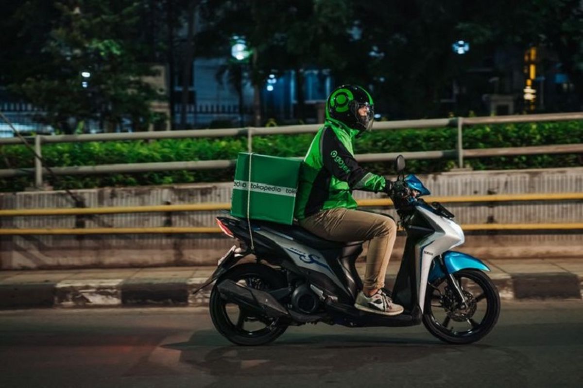 Ilustrasi ojek online yang membawa paket bertuliskan Tokopedia