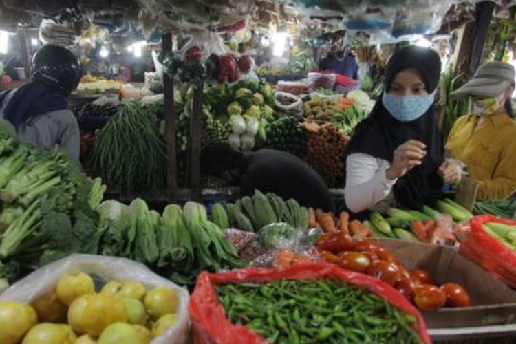 Warga dengan masker memilih sayuran di pasar tradisional Pondok Labu, Jakarta, Minggu (07/06). 