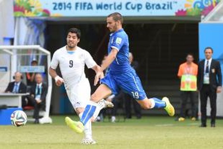 Striker Uruguay, Luis Suarez, saat ingin merebut bola dari kaki bek Italia, Giorgio Chiellini, pada pertandingan terakhir Grup D Piala Dunia 2014 di Estadio Das Dunas, Selasa (24/6/2014). 