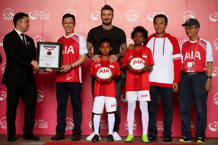 Perwakilan dari Museum Rekor Indonesia (kiri) menyerahkan piagam rekor MURI kepada Presiden Direktur PT. AIA Financial, Ben Ng (kedua dari kiri) disaksikan AIA Global Brand Ambassador David Beckham (tengah), Menteri Pemuda dan Olah Raga Imam Nahrawi (kedua dari kanan), dan Anggota Dewan komisioner Otoritas Jasa Keuangan, Riswinandi saat acara Sepak Bola untuk Negeri di Stadion Soemantri Brodjonegoro, Jakarta, Minggu (25/3/2018). AIA menyerahkan sumbangan 10.000 bola untuk anak-anak akademi sepak bola  di seluruh Indonesia.