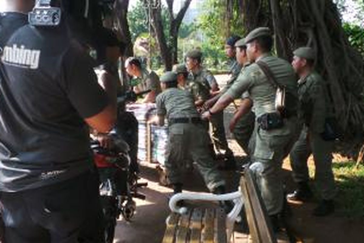 Petugas Satpol PP menyita barang dagangan dari PKL di Monas yang disembunyikan pedagang di semak taman. Sabtu (2/8/2014).