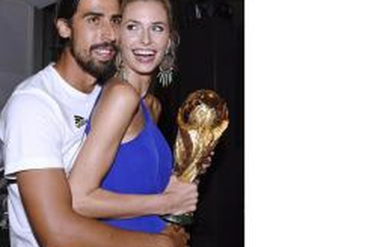 Sami Khedira dan istrinya, Lena Gercke, memegang trofi Piala Dunia dalam pesta yang digelar usai Jerman menjadi juara setelah menang 1-0 atas Argentina di final, Minggu (13/7/2014).