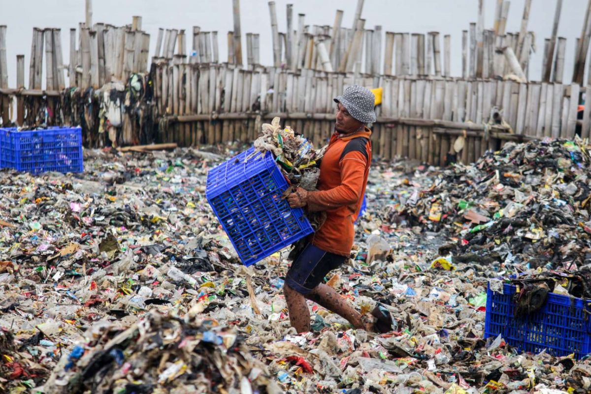 Petugas Suku Dinas Lingkungan Hidup membersihkan sampah plastik yang menumpuk di Kawasan Hutan Bakau Muara Angke, Jakarta, Sabtu (17/3/2018). Sampah yang memenuhi perairan seluas 7.500 meter persegi tersebut terkumpul akibat gulungan ombak yang membawa sampah ke bibir pantai.