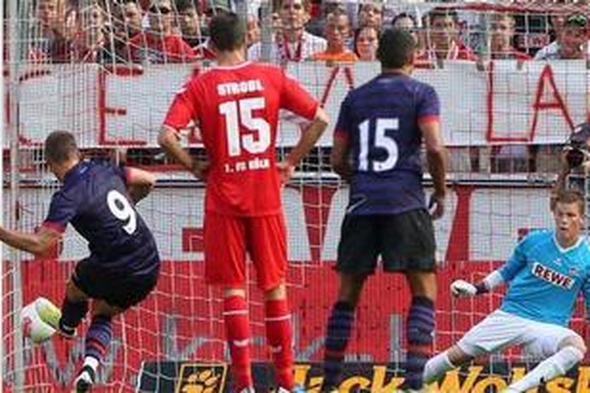 Penyerang Arsenal, Lukas Podolski (kiri), melepaskan tendangan penalti, yang berujung gol ke gawang Koeln, pada laga persahabatan, di Rhein Energie Stadion, Minggu (12/8/2012).