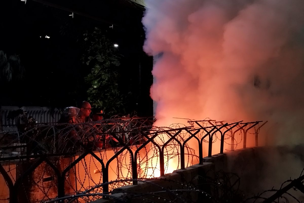 Kapolsek Metro Gambir Kompol Mugia Yarry Junanda membantu memadamkan api yang terbakar di antara beton pembatas menuju Jalan Medan Merdeka Barat, Gambir, Jakarta Pusat, Kamis (10/8/2023). (KOMPAS.com/XENA OLIVIA)
