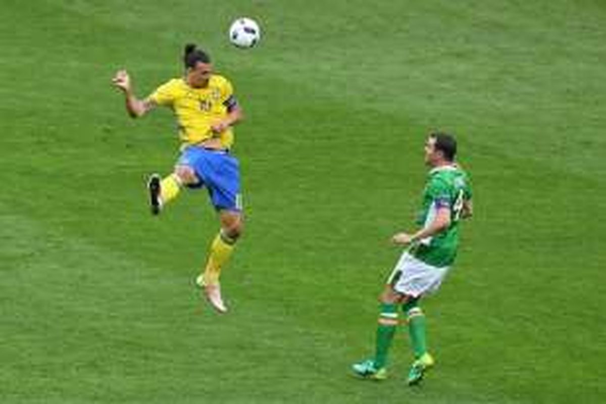 Striker Swedia, Zlatan Ibrahimovic, menyundul bola menjauhi jangkauan bek Irlandia, John O'Shea, saat kedua negara bertemu di Saint-Denis, Senin (13/6/2016).