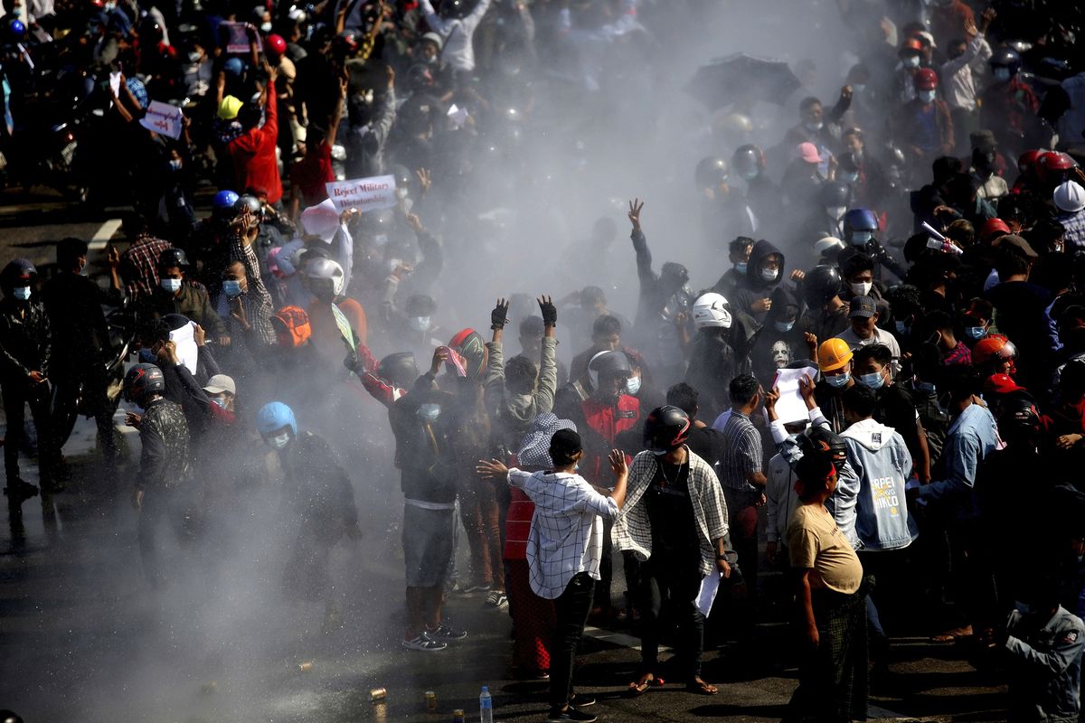 Protesters are sprayed with water fired from a police truck's water cannon in Naypyitaw, Myanmar on Monday, Feb. 8, 2021. Tension in the confrontations between the authorities and demonstrators against last week's coup in Myanmar boiled over Monday, as police fired a water cannon at peaceful protesters in the capital Naypyitaw.(AP Photo)