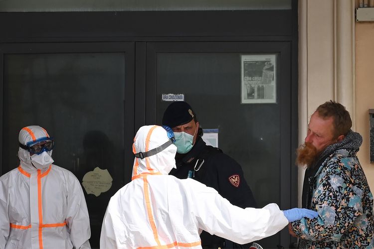 Anggota staf medis yang mengenakan pakaian pelindung menyelamatkan seorang tunawisma di Ostia, luar Roma, pada 21 Maret 2020 di tengah penyebaran virus corona.