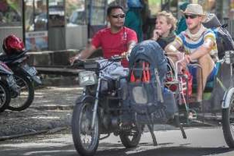 Dua turis asal Jerman berwisata keliling kota menggunakan becak mesin saat melintas di kawasan Blangpadang, Banda Aceh, Selasa (8/4/2014). Turis tersebut dikenakan tarif sebesar Rp. 300.000 hingga Rp 400.000 untuk wisata keliling kota selama satu hari. 