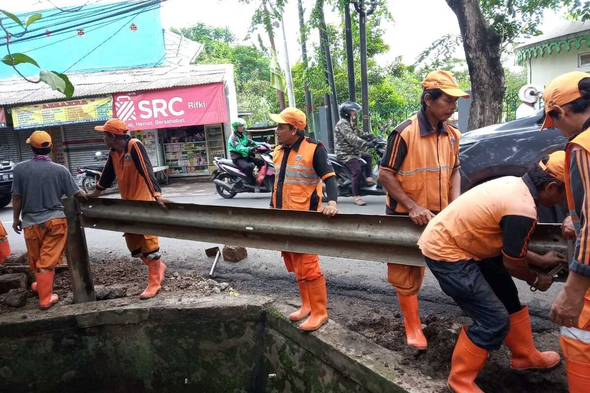 Petugas PPSU Kelurahan Setu saat memasang guard rail di Jalan Raya Pagelarang, Setu, Jakarta Timur, Jumat (31/1/2020).