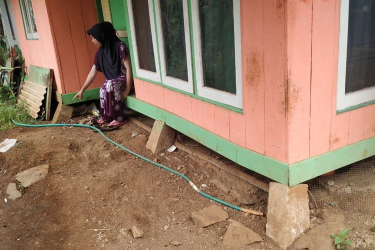 Seorang ibu menunjukan batu fondasi rumah panggungnya yang miring akibat pergerakan tanah di Kampung Batugede, Desa Cimerang, Purabaya, Sukabumi, Jawa Barat, Kamis (6/2/2020).