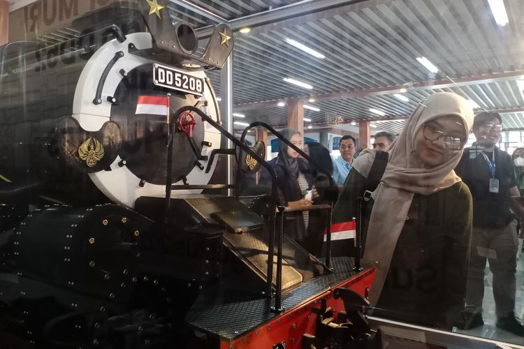 Sejumlah penumpang kereta api melihat miniatur lokomotif terbesar di Indonesia di Stasiun Gubeng, Surabaya, Jumat (4/8/2023).