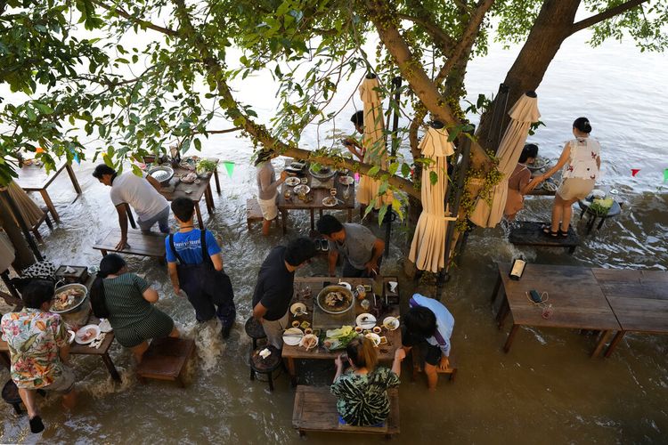 Para pelanggan Chaopraya Antique Cafe di tepi sungai bereaksi ombak saat mereka menikmati hidangan di Sungai Chao Phraya di Nonthaburi, dekat Bangkok, Thailand, Kamis (7/10/2021).