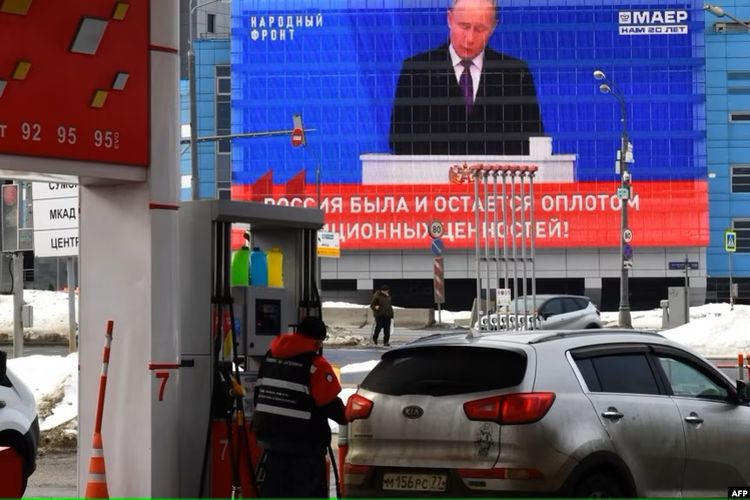 Sebuah layar menampilkan siaran pidato kenegaraan tahunan Presiden Rusia Vladimir Putin, saat seorang karyawan mengisi BBM di sebuah pompa bensin di Moskwa, 29 Februari 2024.