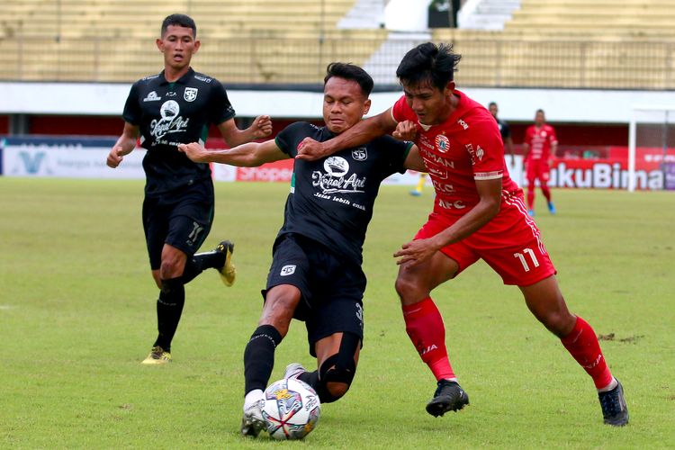 Pemain Persija Jakarta Firza Andika merebut bola pemain Persebaya Surabaya Koko Ari Araya saat pertandingan penan ke-15 Liga 1 2022-2023 yang berakhir dengan skor 1-1 di Stadion Maguwoharjo Sleman, Jumat (16/12/2022) sore.