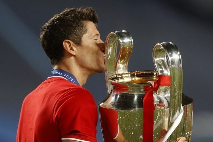 Penyerang Bayern Muenchen, Robert Lewandowski mencium trofi Liga Champions pertamanya.
