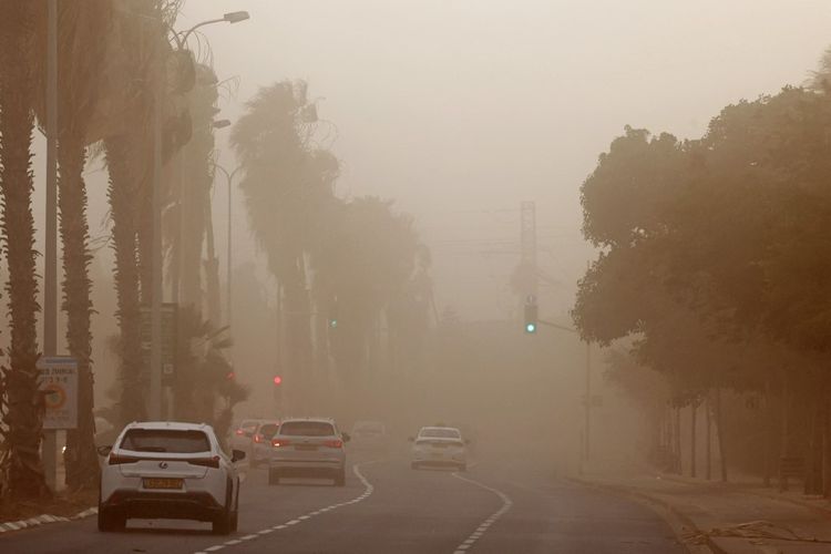 Pengemudi berkendara saat badai pasir di Tel Aviv pada 1 Juni 2023. (Foto oleh JACK GUEZ / AFP)