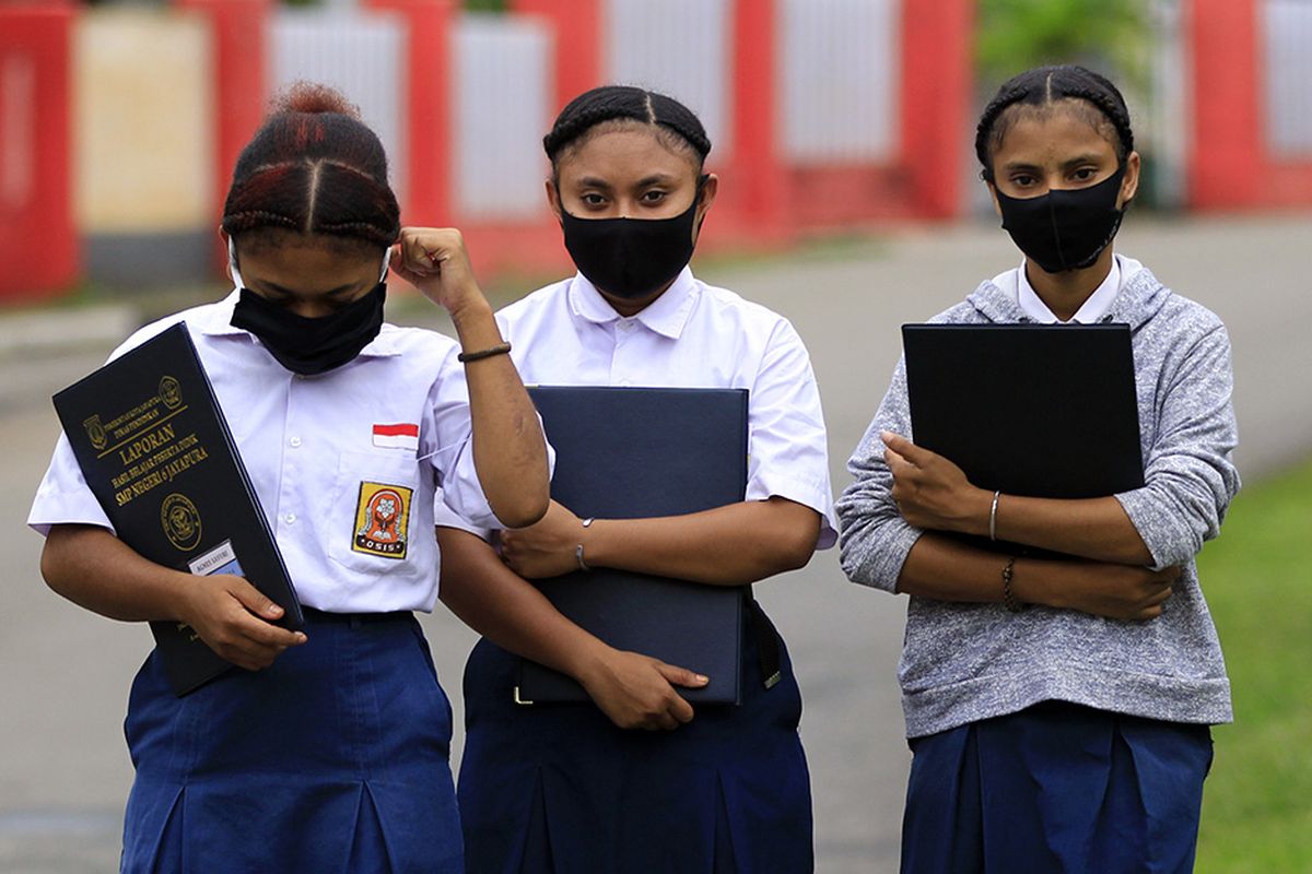 Siswa SMP Negeri 6 Jayapura dengan masker di wajahnya berjalan meninggalkan sekolah usai melakukan pendaftaran ulang pada hari pertama sekolah di Jayapura, Papua, Senin (13/7/2020). Siswa SD, SMP dan SMA mulai mengikuti kegiatan belajar-mengajar tahun ajaran baru 2020/2021 dengan sistem pembelajaran tatap muka langsung dan daring.