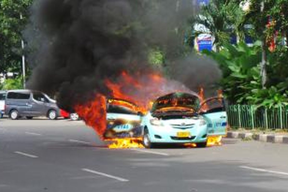 Sebuah taksi yang terbakar di depan Gedung Kemenpora, Senayan, Jakarta, Senin (27/1/2014).