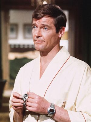 Roger Moore mengenakan Hamilton Pulsar LED sambil memegang arloji Submariner di Live and Let Die, 1973