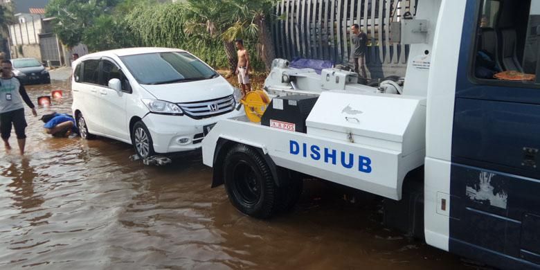 Mobil derek Dinas Perhubungan DKI Jakarta, Sabtu (4/6/2016), menarik mobil milik warga yang terendam banjir akibat tanggul jebol di Pantai Mutiara, Penjaringan, Jakarta Utara, pada Jumat malam sebelumnya.
