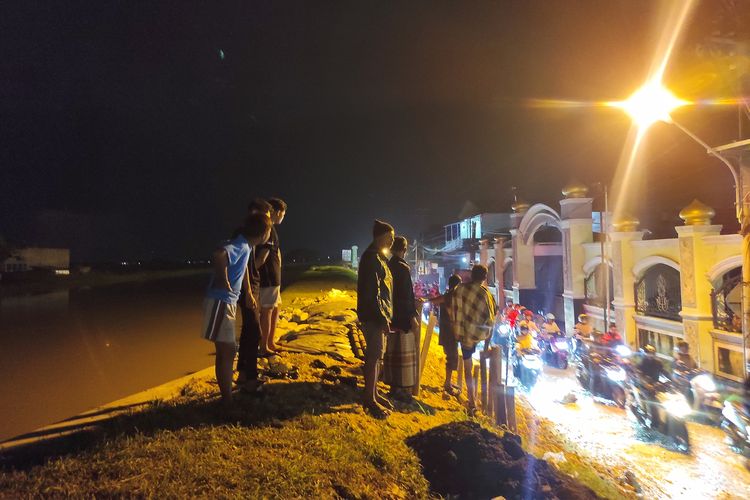 Warga nampak mengecek kondisi tanggul yang merembes di depan Masjid Karanganyar, Jumat (15/3/2024) malam.  