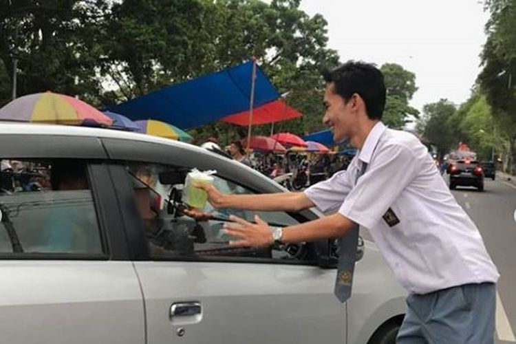 Salah satu siswa tengah membagikan takjil gratis kepada pengemudi di sekitar sekolah, sebagai rasa syukur kelulusan yang diterima.