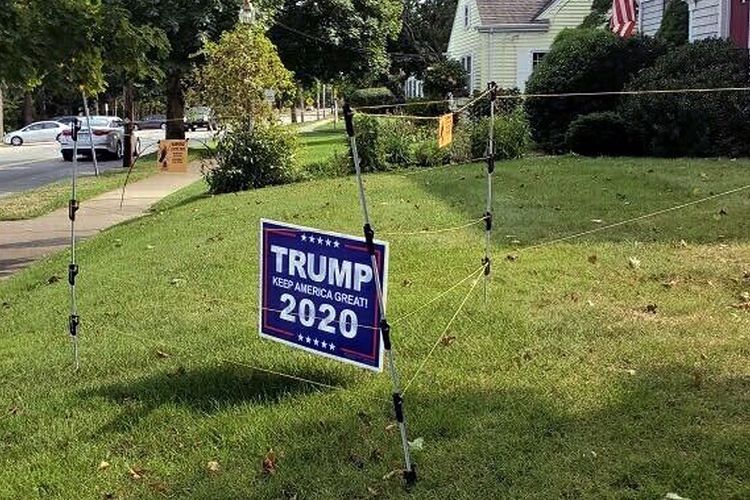 Dalam foto 14 September 2020 ini, pagar listrik mengelilingi tanda kampanye untuk Presiden Donald Trump di halaman John Oliveira di New Bedford, AS.