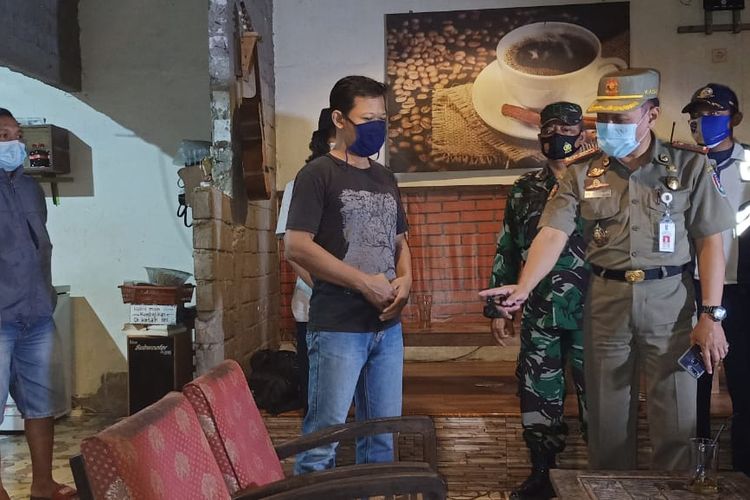 Kasatpol PP Kabupaten Tuban, Heri Muharwanto melakukan penindakan terhadap pemilik warung kopi dalam razia protokol kesehatan, Sabtu (30/12021) malam.
