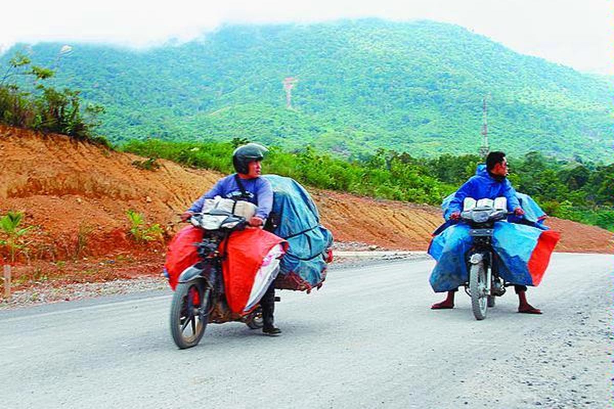 Dua warga Kabupaten Sambas, Kalimantan Barat, melintasi jalan akses perbatasan yang menghubungkan wilayah Indonesia dan Malaysia. Mereka baru saja pulang dari Biawak, Malaysia, untuk membeli barang kebutuhan sehari-hari.