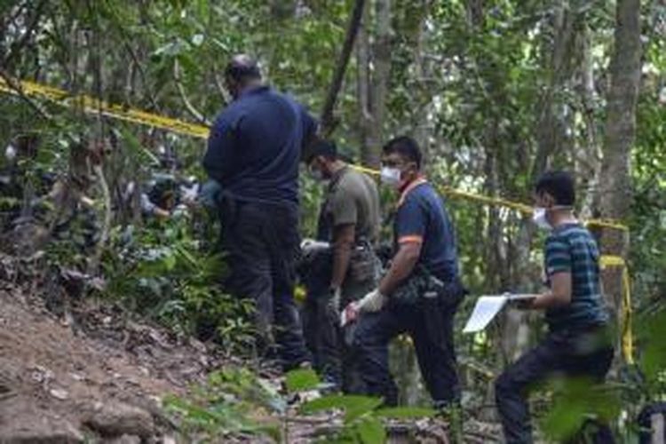 Tim forensik Kepolisian Kerajaan Malaysia membongkar kuburan massal di hutan Bukit Wang Burma di Perlis, negara bagian utara Malaysia, yang berbatasan dengan Thailand, 26 Mei 2015.