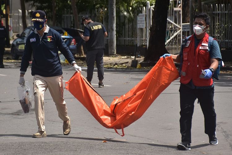 Police investigators carry a body bag containing the remains of two suicide bombers who carried out an attack on Makassar Cathedral during a Palm Sunday Mass on Sunday morning (28/3/2021). The two attackers were the only fatalities in the attack, which also wounded 20 members of the church congregation as well as the cathedral's security guards.