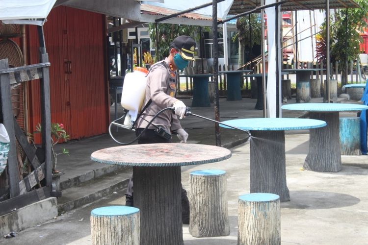 Kapolres Mempawah AKBP Tulus Sinaga menempel lakban dan menyemprotkan disenfektan di meja dan kursi pedagang di kawasan kuliner Terminal Mempawah, Kalimantan Barat, kemarin.
