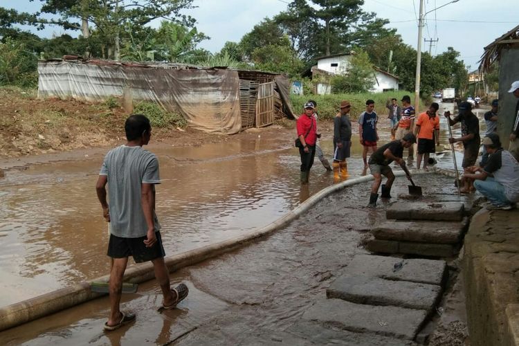 Warga dan petugas gabungan tengah membersihkan endapan lumpur setebal 25 cm pascabanjir di Kabupaten Bandung.