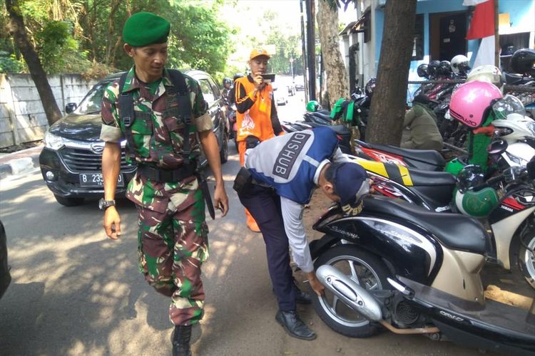 Petugas Dishub cabut pentil ban motor yang terparkir di trotoar di kawasan Pasar Minggu, Jakarta Selatan, Selasa (9/7/2019)