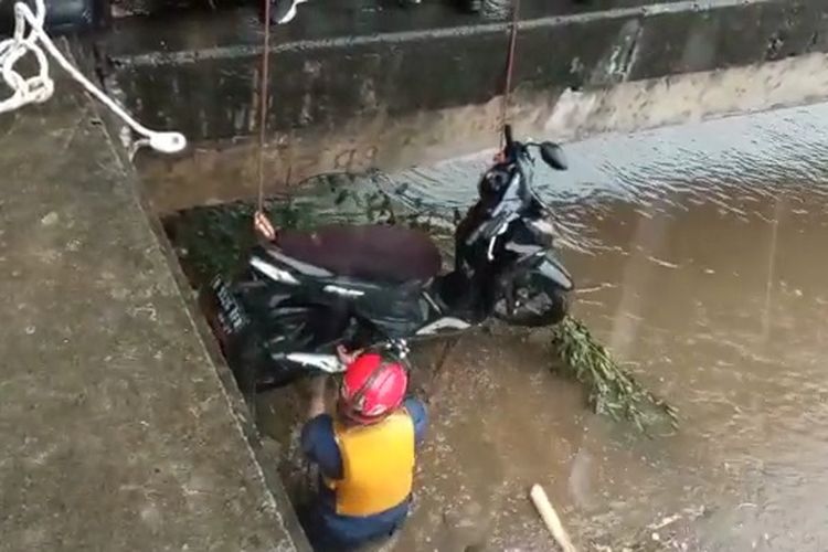 Petugas penyelamat dari Sudin Gulkarmat Jakarta Barat melakukan evakuasi motor yang tercemplung ke Kali Cengkareng Drain saat tengah berkendara di Jalan Kali Kapuk Timur, Kapuk, Cengkareng, Jakarta Barat, Kamis (13/10/2022) sore.