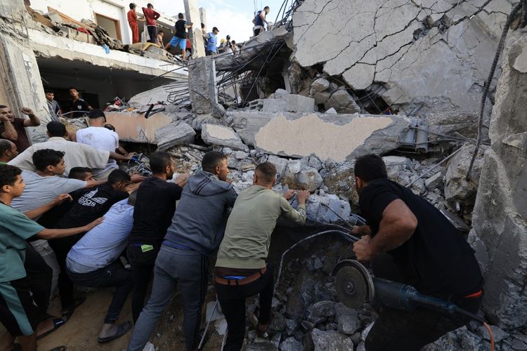 Perang Hamas vs Israel terkini, warga Palestina mencari di antara reruntuhan bangunan setelah serangan Israel di Khan Yunis di Jalur Gaza selatan pada 17 Oktober 2023.