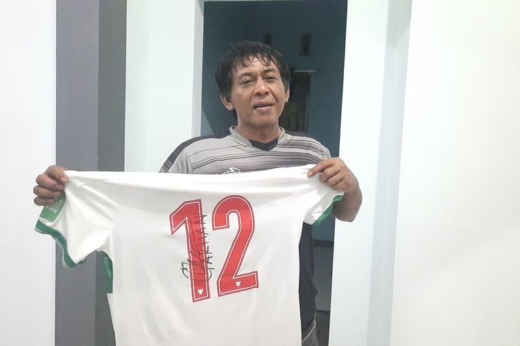 Lulus Widodo memamerkan jersey kaos timnas yang diberikan oleh eks anak didiknya yang juga pemain timnas, Pratama Arhan saat ditemui kompas.com di rumahnya, Minggu (6/3/2022)