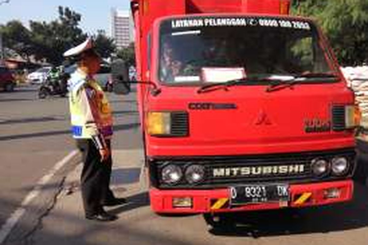 Petugas kepolisian sedang menegur pengemudi kendaraan berpelat nomor genap di lampu merah Simpang Kuningan pada Kamis (28/7/2016).