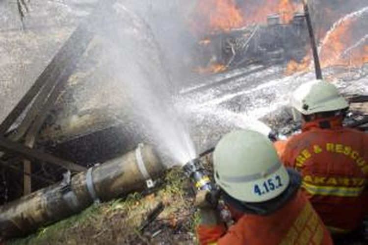 Petugas memadamkan api di lokasi tabrakan kereta rel listrik (KRL) jurusan Serpong-Tanah Abang dan truk tangki pengangkut bahan bakar di pelintasan Pondok Betung, Bintaro, Jakarta Selatan, Senin (9/12/2013). Kecelakaan mengakibatkan sejumlah rangkaian gerbong dan truk tangki terbakar serta menyebabkan dua orang tewas dan puluhan orang mengalami luka bakar. 