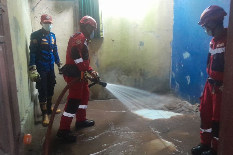 Petugas pemadam kebakaran membersihkan lumpur di rumah Dokter Wayan, Jumat (5/5/2023).