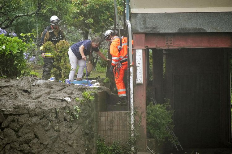 Petugas pemadam kebakaran membantu seorang warga mengungsi setelah tanah longsor di distrik Izusan di Atami, barat Tokyo, Sabtu, 3 Juli 2021, menyusul hujan lebat di daerah tersebut. 