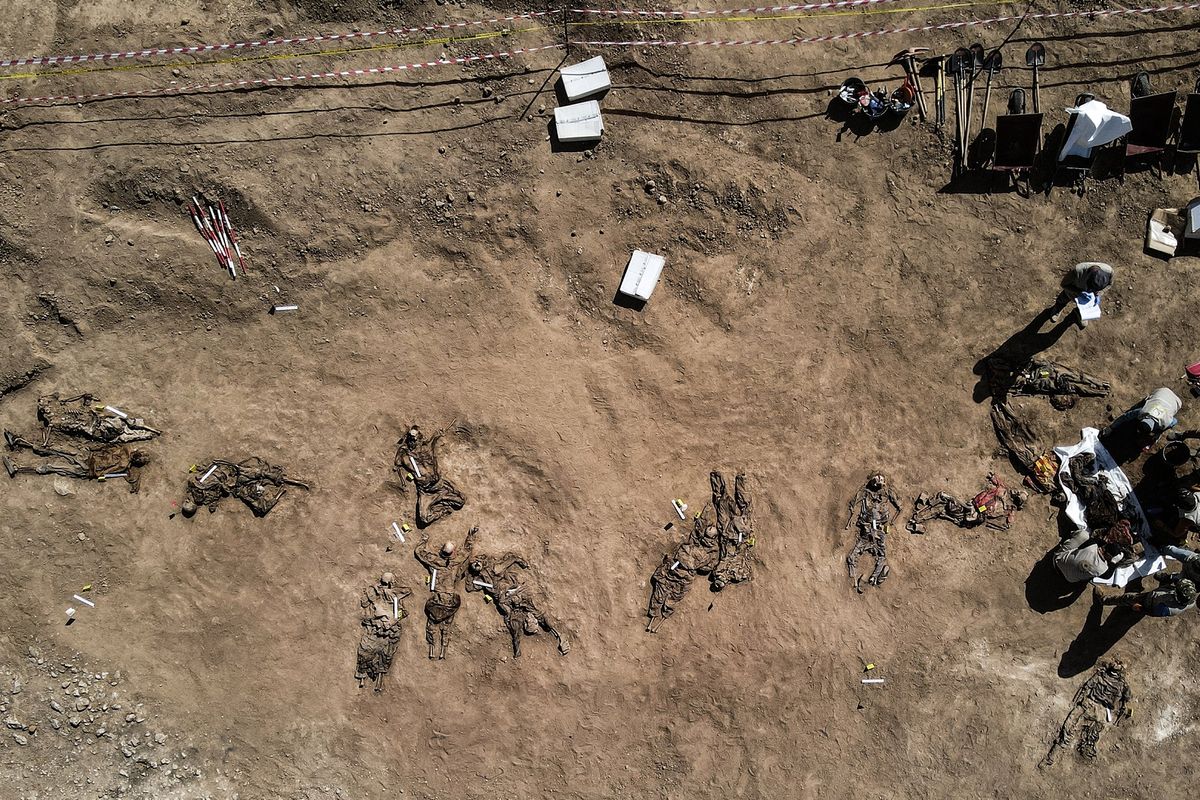 Foto udara yang diambil pada 13 Juni 2021 menunjukkan kerangka manusia yang diyakini korban ISIS dalam pembantaian Penjara Badush 2014 diangkat dari kuburan massal di sebelah barat laut Mosul, Irak. Di Juni 2014, anggota ISIS menyerang penjara itu, membawa hampir 600 tahanan yang mayoritas Syiah ke truk, membawa mereka ke sebuah jurang, dan membunuh mereka di sana.